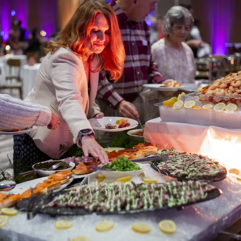 Woman serving herself shrimp at Mother's Day Brunch in Canyon Ballroom.