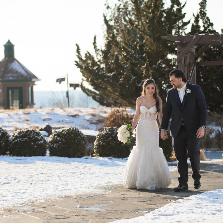 Bride and groom walk along a snowy path.