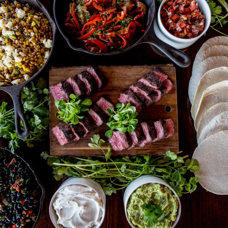 Cut up steak, corn, beans, guac, salsa and tortilla shells.