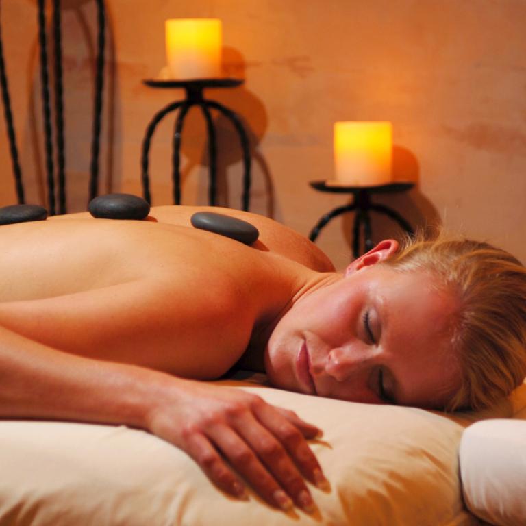 Woman laying on table with hot stones on her back during spa getaway. 