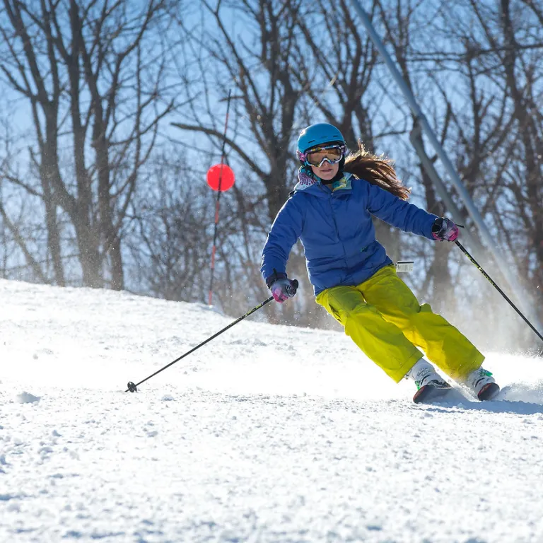 Person in blue jacket skiing down mountain.