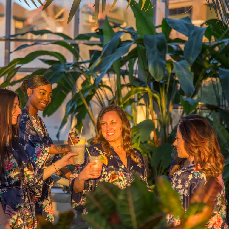 Four women in floral robes drinking in the Biosphere during girlfriends getaway.