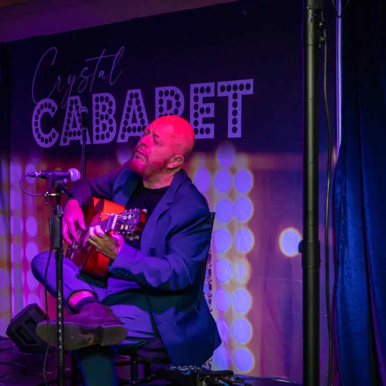 Hernan Romero playing guitar on stage at Crystal Cabaret.