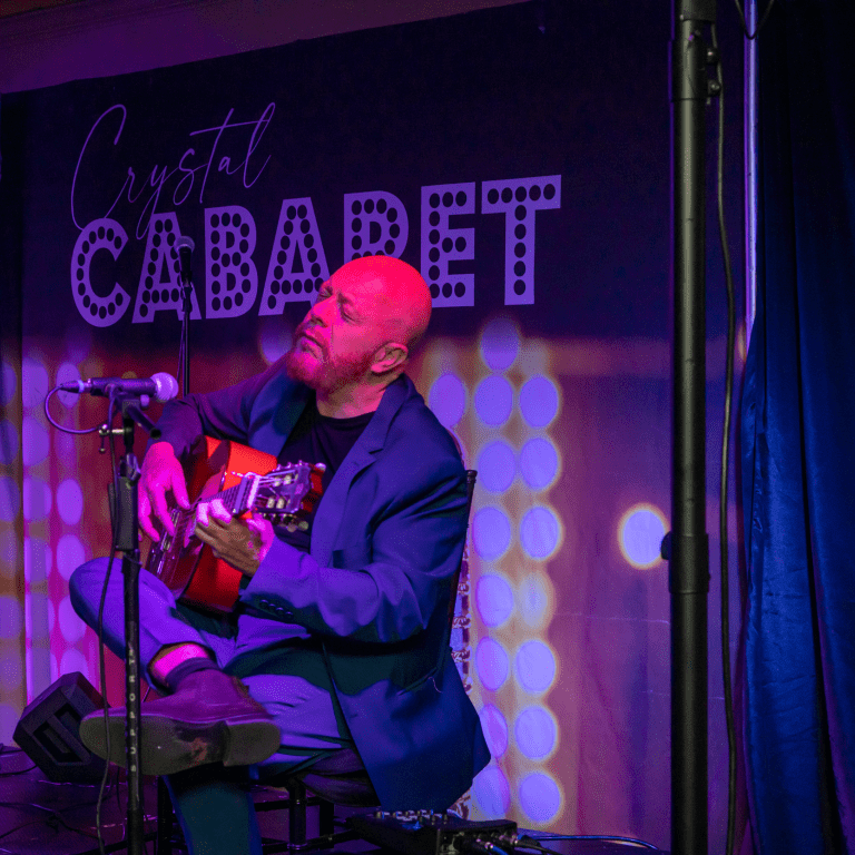 Hernan Romero playing guitar on stage at Crystal Cabaret.