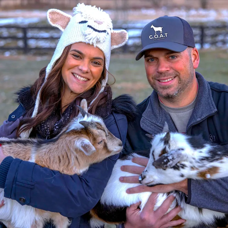 Couple holding baby goats.