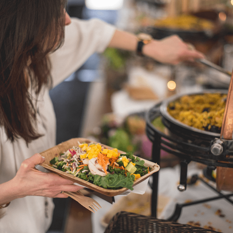 Woman scooping rice onto her plate during buffet.