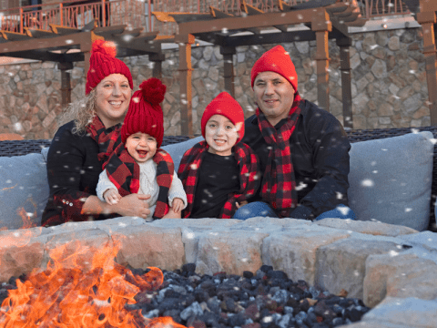 Family of four bundled up by the fire. 