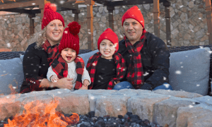 Family of four bundled up by the fire. 