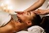 Woman laying on table with facialists hands on her chin and forehead. 