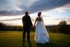 Bride and groom stand hand in hand looking at one another