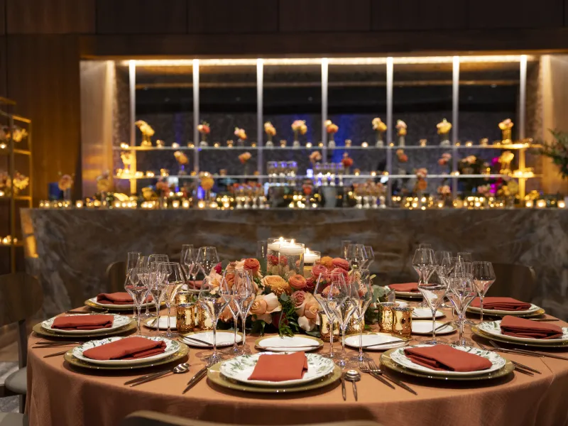 Table set up featuring orange and pink flowers in the Canyon Ballroom for wedding reception.