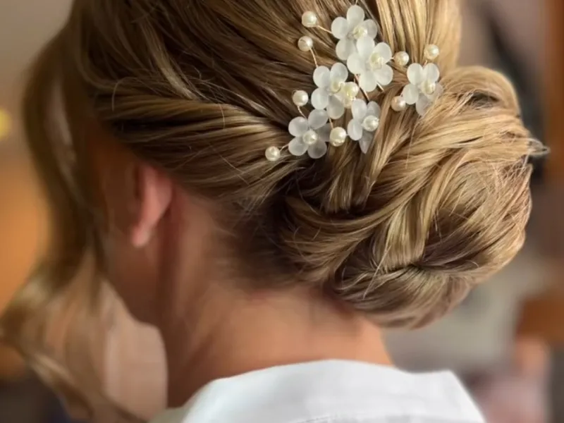 Up do hairstyle featuring gold flower. 