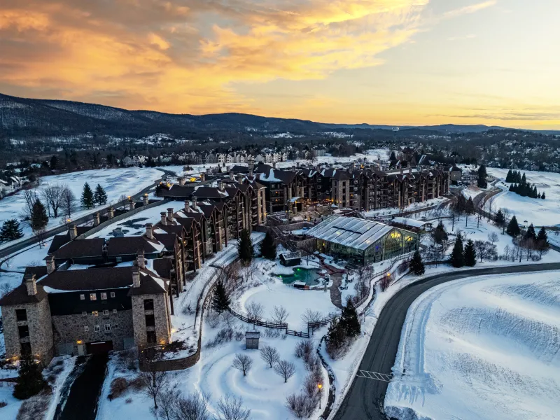 Drone shot of Grand Cascades Lodge showing snow and sunset. 