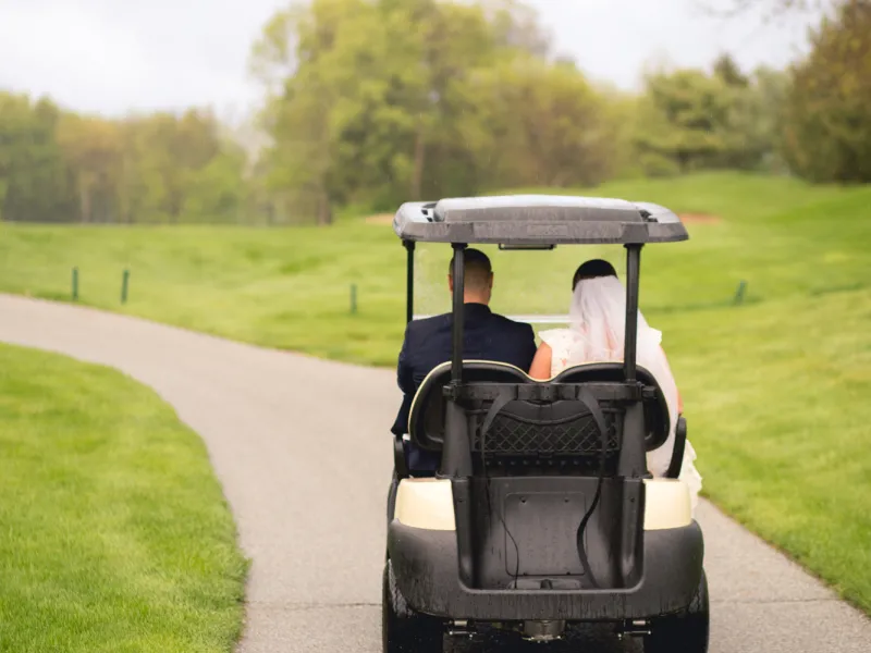 Bride and groom riding away in golf cart