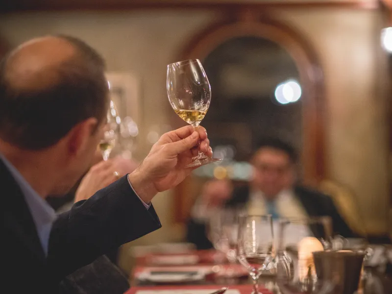 Man holding up glass filled with white wine.