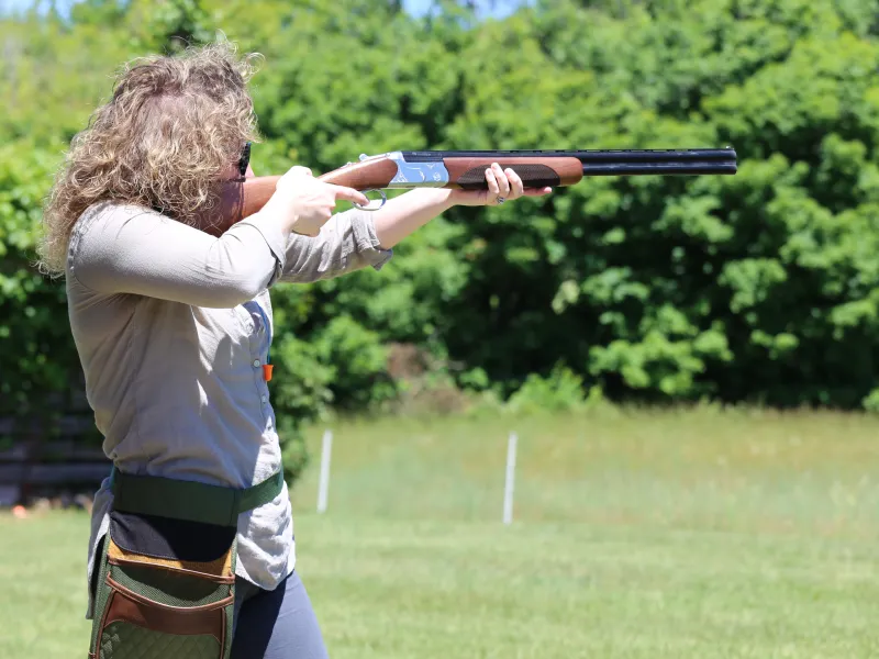 Woman shooting laser gun at clay targets.