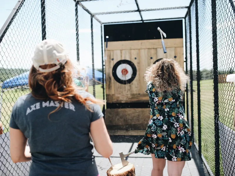 Woman throwing axe at target.