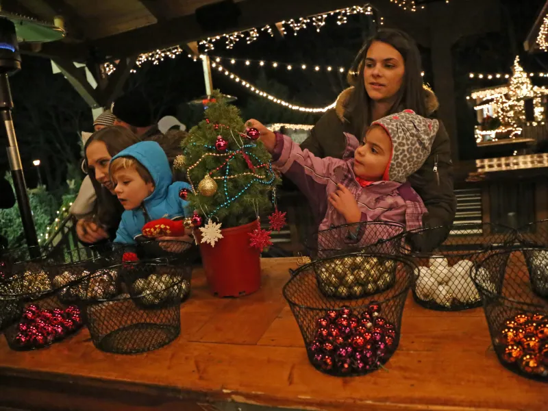 Young children decorating mini trees with bulbs.