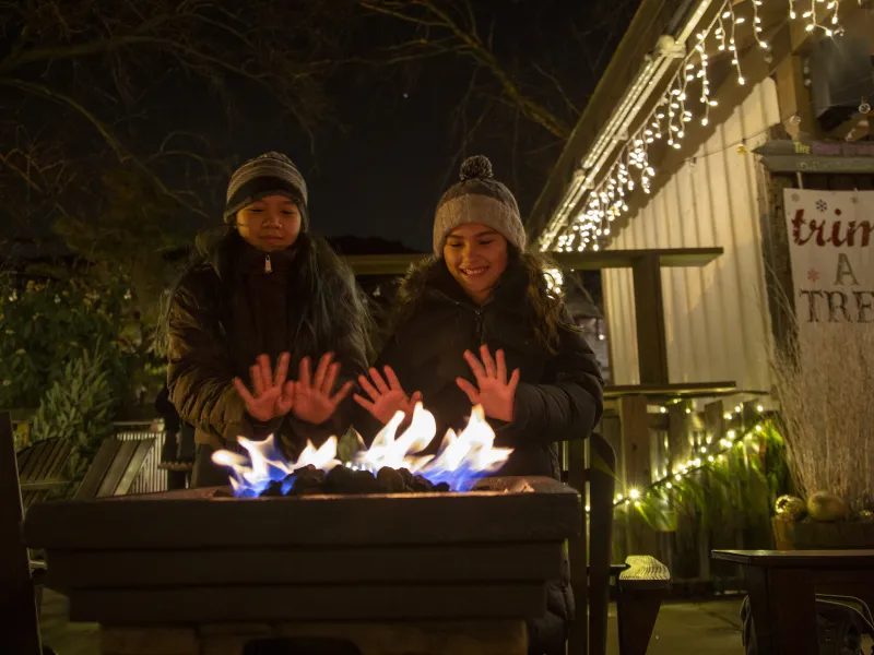 Two people warming hands up by fire.