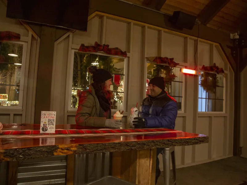 Couple bundled up and drinking warm beverages at Frosty's Cantina.