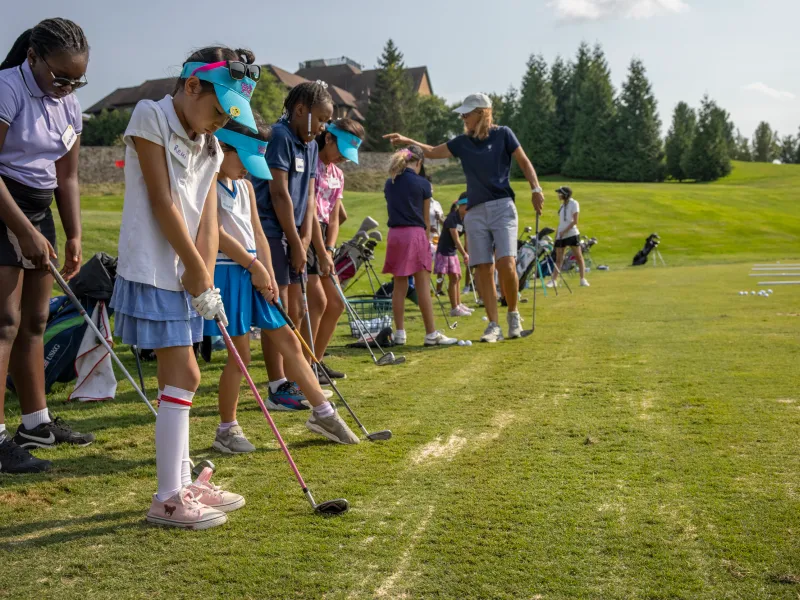 Golf instructor teaching young girls how to golf