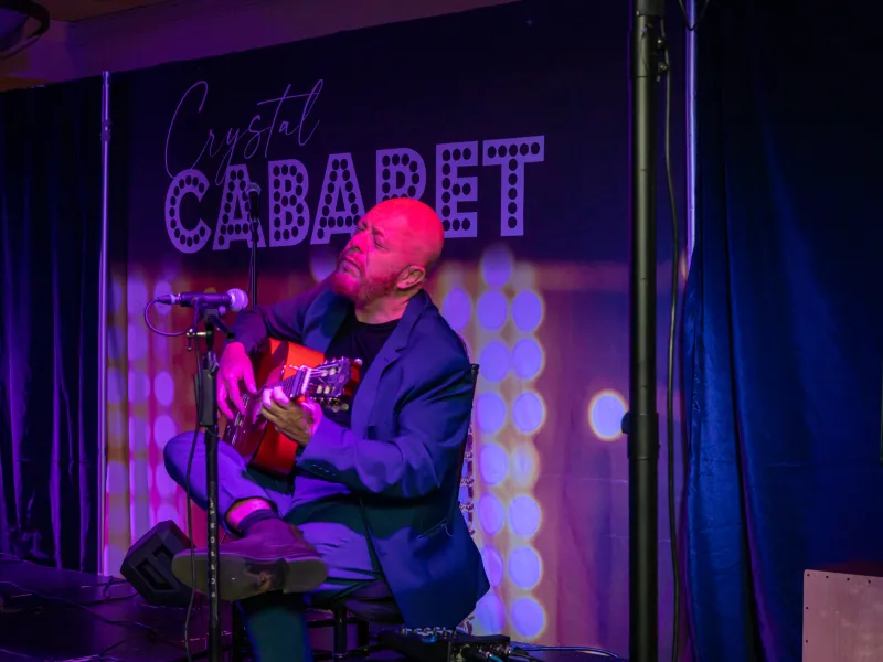 Hernan Romero playing guitar on stage at Crystal Cabaret.