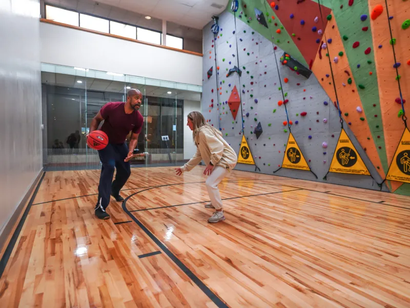 Two people playing basketball at indoor court.