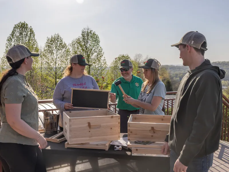 Group of people learning how to build a bee hive box.